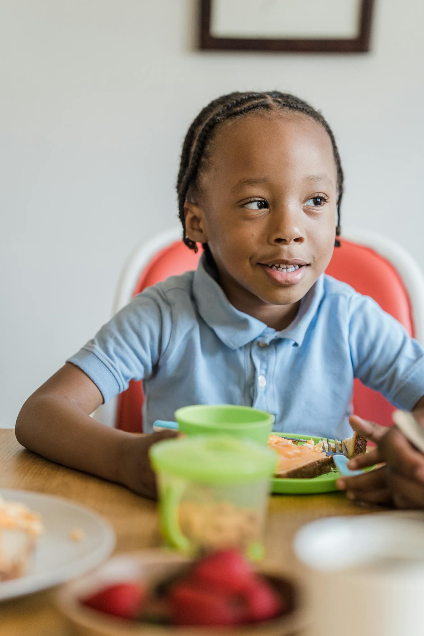Young boy having a cheerful breakfast with fresh strawberries at a home kitchen table.